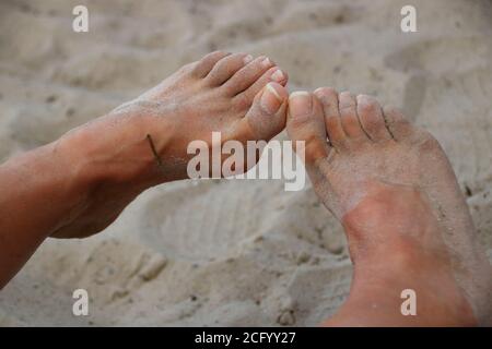 Feet on a sandy beach are covered with sand Stock Photo
