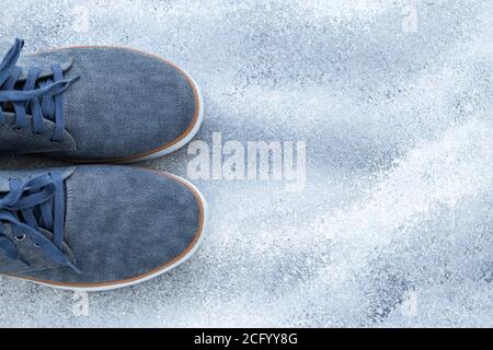 A pair of men's shoes, blue denim sneakers on a gray background. Comfortable textile footwear. Top view. Casual fashion style concept. Empty place for Stock Photo