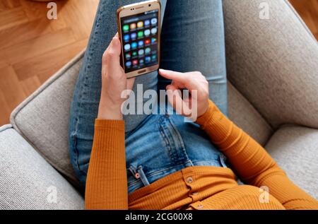 Closeup of young woman from above using smart phone at home yellow orange colors Stock Photo