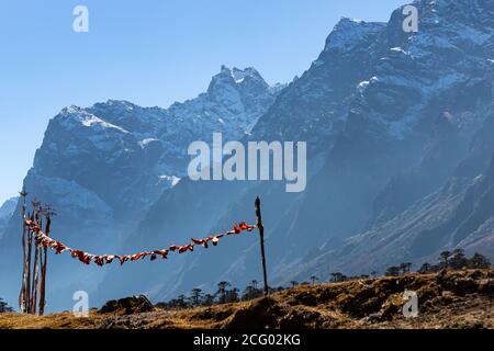 Tibetan prayer flags blowing with the wind with high mountain ranges in the background back lit with sun at the valley of flowers in Sikkim India Stock Photo