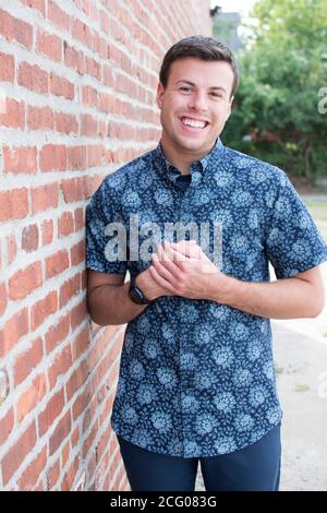 A Portrait of a man in a blue button down shirt against a brick wall Stock Photo