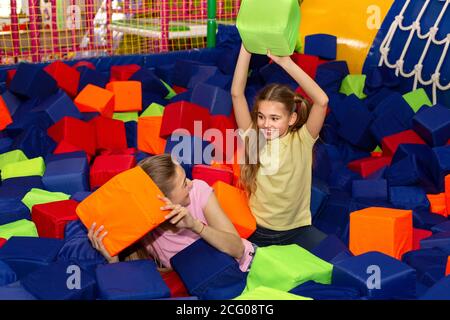 Lovely girl and her mom having lots of fun playing with soft cubes at indoor kids centre, copy space Stock Photo