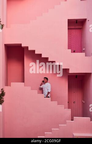 Young latin man talks on his mobile in a pink building Stock Photo