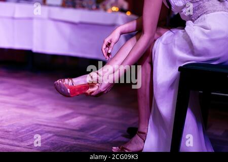 Close up of a woman in an evening dress wearing her shoe Stock Photo