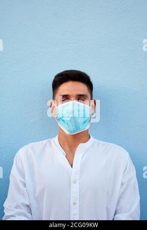Young latin man with mask on blue background Stock Photo