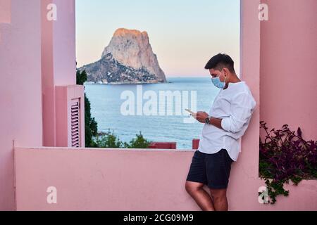 Young man holds his mobile in a pink building Stock Photo