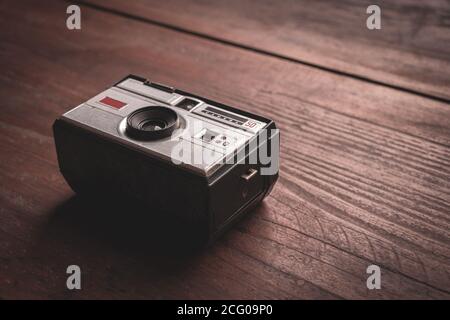 Old and worn photo camera from the 60s on rustic wooden table Stock Photo