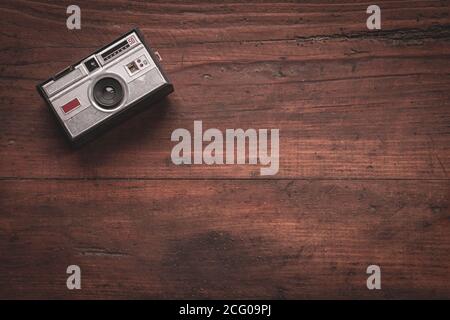 Old and worn photo camera from the 60s on rustic wooden table Stock Photo