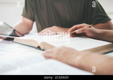 Learning, education and school concept. Young woman and man studying for a test or an exam. Tutor books with friends. Young students campus helps frie Stock Photo