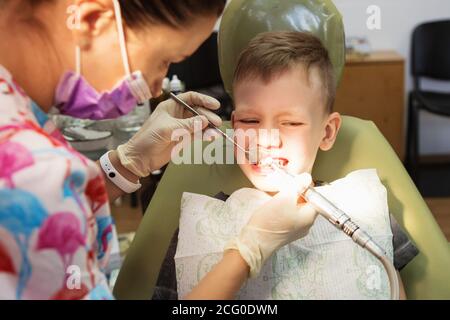 A little boy at a dentist's reception in a dental clinic. Children's dentistry, Pediatric Dentistry. A female stomatologist  is treating teeth of a sc Stock Photo
