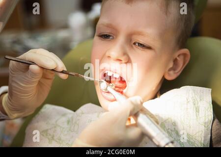 A little boy at a dentist's reception in a dental clinic. Children's dentistry, Pediatric Dentistry. A female stomatologist  is treating teeth of a sc Stock Photo