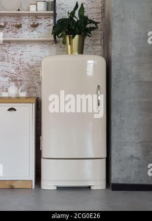 Vertical shot of vintage fridge in kitchen with grunge walls Stock Photo