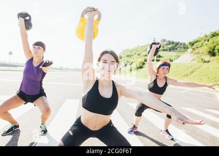 Healthy young athletes doing exercises with kettlebells, at fitness studio. Stock Photo