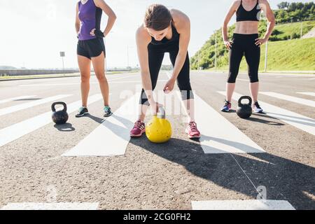 Healthy young athletes doing exercises with kettlebells, at fitness studio. Stock Photo