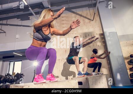 Male and female athletes doing box jumps at gym Stock Photo