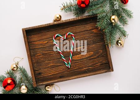 Christmas frame. Christmas balloons, garlands, red and gold ornaments, Christmas candles and fir branches with a brown wooden tray on a white backgrou Stock Photo