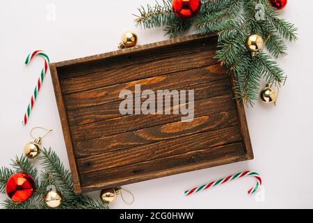 Christmas frame. Christmas balloons, garlands, red and gold ornaments, Christmas candles and fir branches with a brown wooden tray on a white backgrou Stock Photo