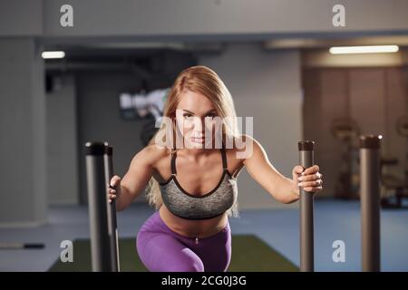 Muscular and strong young female pushing the prowler exercise