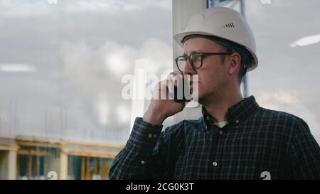 Engineer making call while standing at construction area. Stock Photo