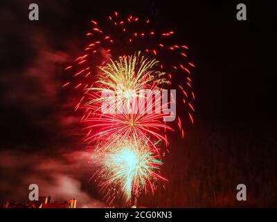 Bright flare of fireworks in red shades against a dark sky Stock Photo