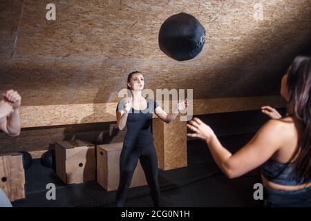 training together at gym banner panoramic crop. Two fit people throwing medicine ball at each other in fitness center cross training core exercise. Wo Stock Photo