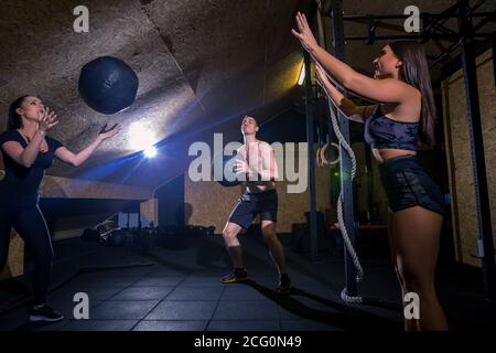 training together at gym banner panoramic crop. Two fit people throwing medicine ball at each other in fitness center cross training core exercise. Wo Stock Photo