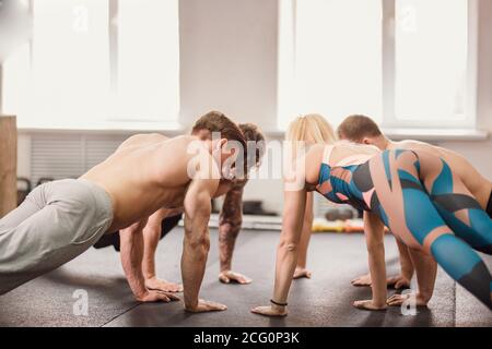 Group of sportive people training in a gym - group of athletes doing push ups in circle Stock Photo