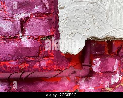 View on isolated rough brick wall painted in white, pink, purple and white color with water pipe (Focus on white wall right) Stock Photo