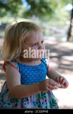 2 yr old toddler girl in a sundress looking sad Stock Photo