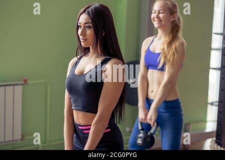 Healthy young athletes doing exercises with kettlebells, at fitness studio Stock Photo