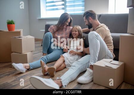 Dad and mom tickling their daughter and smiling Stock Photo