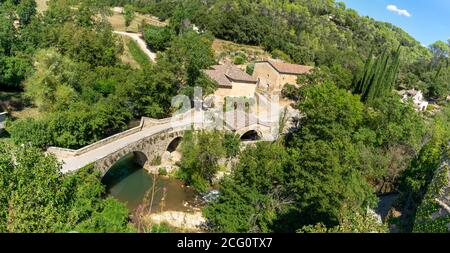 panoramic view of a small village in the south-east of France. a river flows under an old stone bridge on a sunny day Stock Photo