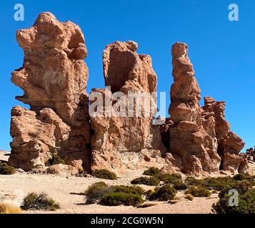 Three Giants. Red rocks in desert Siloli. Impressive rock formations. Geological rock formations in Valle de Rocas, Uyuni, Bolivia. Volcanic stones. Stock Photo