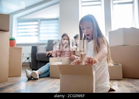 Cute girl unpacking a cardboard and looking surprised Stock Photo