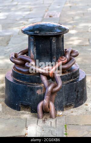An old capstan with a rusty metal chain around it, Part of the Portsmouth Chain link walk Stock Photo