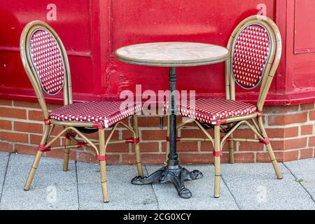 Two empty dining chairs either side of a table outside a restaurant or cafe Stock Photo