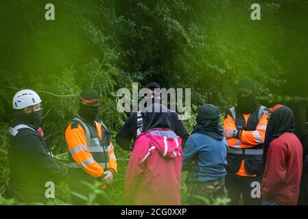 Denham, UK. 8th September, 2020. National Eviction Team enforcement agents and HS2 security guards stand in the river Colne to prevent HS2 Rebellion activists from supporting a fellow activist who had climbed a tree in Denham Country Park in order to try to protect it from works for the HS2 high-speed rail link. Anti-HS2 activists continue to try to prevent or delay works on the controversial £106bn project for which the construction phase was announced on 4th September from a series of protection camps based along the route of the line between London and Birmingham. Credit: Mark Kerrison/Alam Stock Photo
