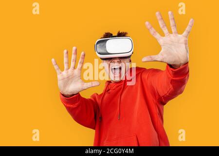 Young adult model man in vr glasses standing against orange background Stock Photo