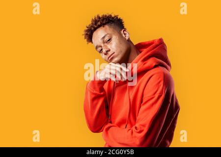 Freestyle. Mulatto freckled guy in hoodie standing isolated on yellow posing to camera playful Stock Photo
