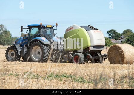 Baling straw rolls in the English countryside Stock Photo