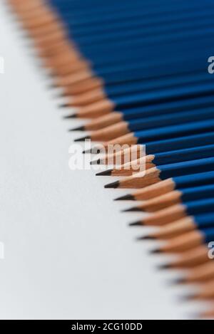 Close up of tops of new blue sharpened pencils on white paper. Stock Photo