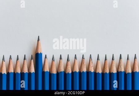 Row of tops of many new sharpened blue pencils against white paper. Stock Photo