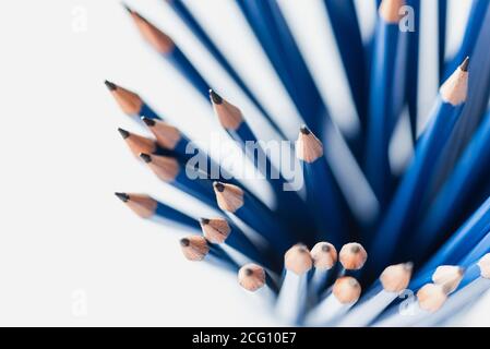 Overhead view of bunch of sharpened blue pencils on white paper. Stock Photo