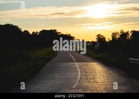 Sun reflecting on a countryside road, car speeding in the curve. Summer, country, travel, speed setting Stock Photo