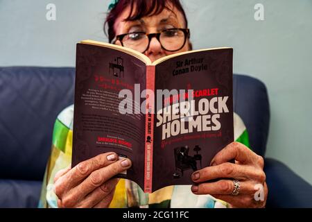 Elderly woman reading Sherlock Holmes A study in scarlet Stock Photo