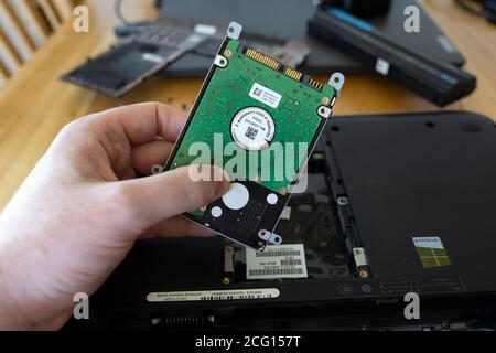 Man's hand holding a Seagate 2.5" hard disk drive (HDD) removed from a laptop. Theme: data storage, computer repair, old technology superseded, memory Stock Photo