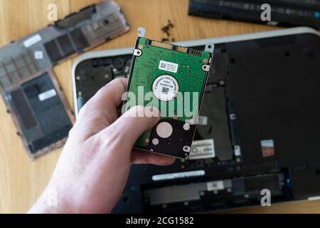 Man's hand holding a Seagate 2.5" hard disk drive (HDD) removed from a laptop. Theme: data storage, computer repair, old technology superseded, memory Stock Photo