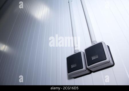 The waterproof light switch is mounted on the sandwich panel wall. Electrical equipment in a production building. Stock Photo