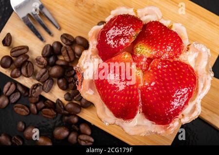 Tasty cupcake with fruit on a wooden board. Dessert prepared for serving. Dark background. Stock Photo