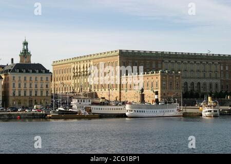 Boats moored beside the Royal Palace, Kungliga Slottet, Gamla stan Stockholm viewed from Skeppsholmsbron. on sunny autumn day. Stock Photo